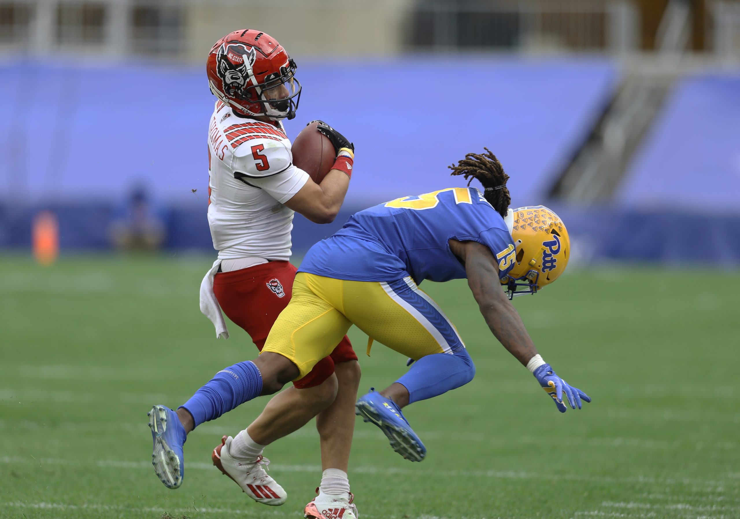 Oct 3, 2020; Pittsburgh, Pennsylvania, USA; North Carolina State Wolfpack wide receiver Thayer Thomas (5) runs through a tackle attempt by Pittsburgh Panthers defensive back Jason Pinnock (15) after a catch during the fourth quarter at Heinz Field. The Wolfpack won 30-29.
