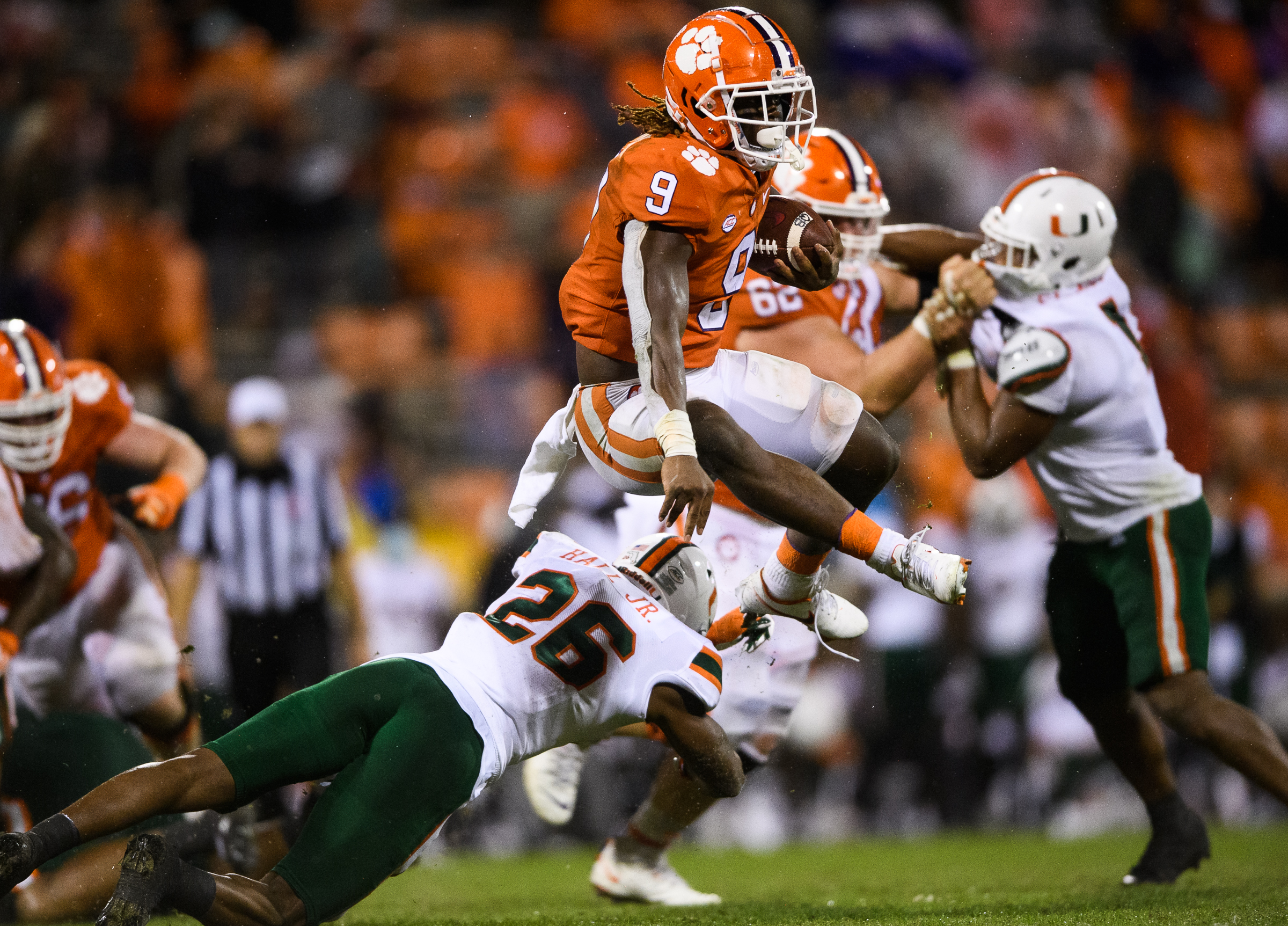 Oct 10, 2020; Clemson, South Carolina, USA; Clemson Tigers running back Travis Etienne (9) leaps over Miami Hurricanes safety Gurvan Hall, Jr. (26) during the third quarter at Memorial Stadium.