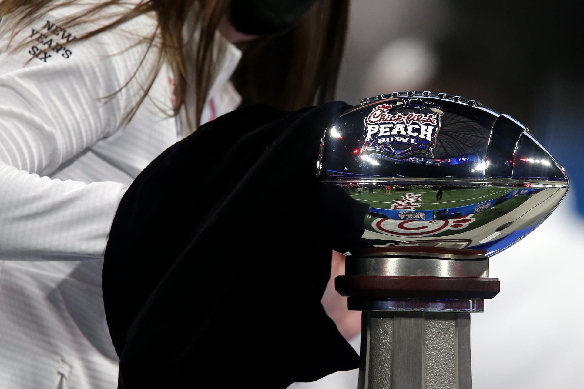 A staff member polishes the trophy before the presentation at the conclusion of the Chick-fil-A Peach Bowl, Friday, Jan. 1, 2021, at Mercedes-Benz Stadium in Atlanta, Georgia. The Georgia Bulldogs won.