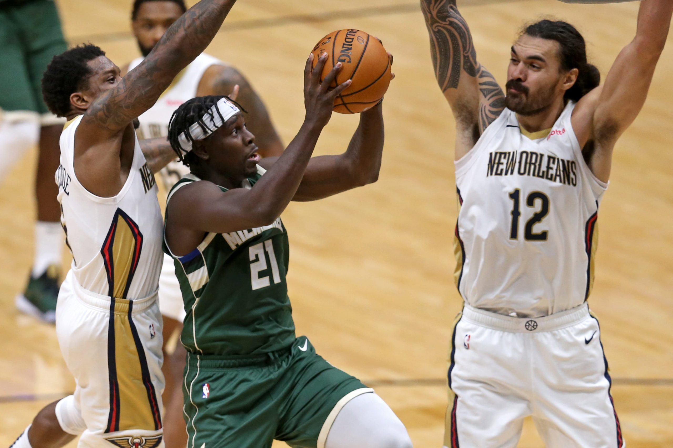 Milwaukee Bucks guard Jrue Holiday (21) drives against New Orleans Pelicans guard Eric Bledsoe (6) and center Steven Adams (12) in the second half at the Smoothie King Center.