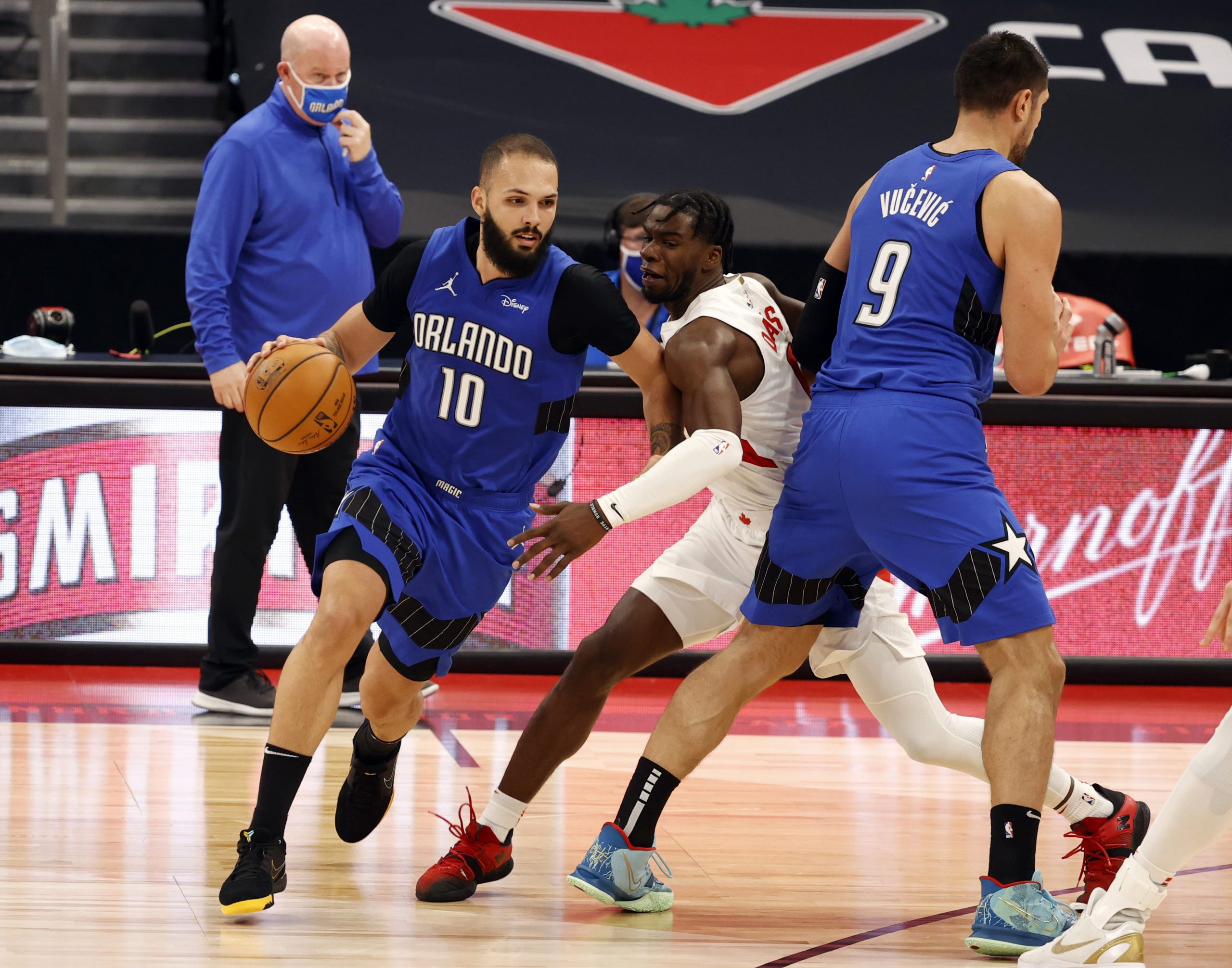 Orlando Magic guard Evan Fournier (10) drives to the basket around center Nikola Vucevic (9) and Toronto Raptors guard Terence Davis (middle) during the second half at Amalie Arena.