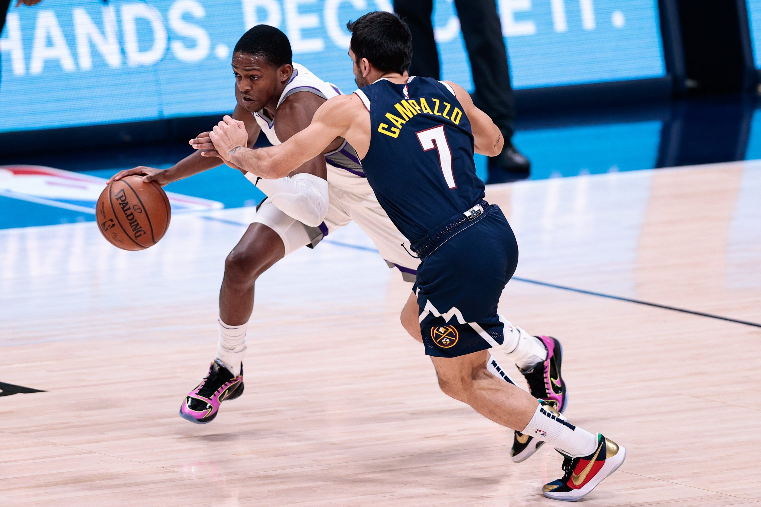 Sacramento Kings guard De'Aaron Fox (5) controls the ball as Denver Nuggets guard Facundo Campazzo (7) guards in the third quarter at Ball Arena.