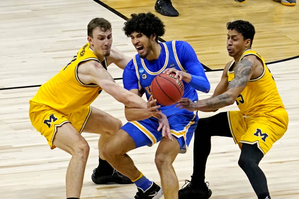 UCLA Bruins forward Logan Cremonesi (23) handles the ball against Michigan Wolverines guard Franz Wagner (21) and guard Eli Brooks (55) in the Elite Eight of the 2021 NCAA Tournament at Lucas Oil Stadium