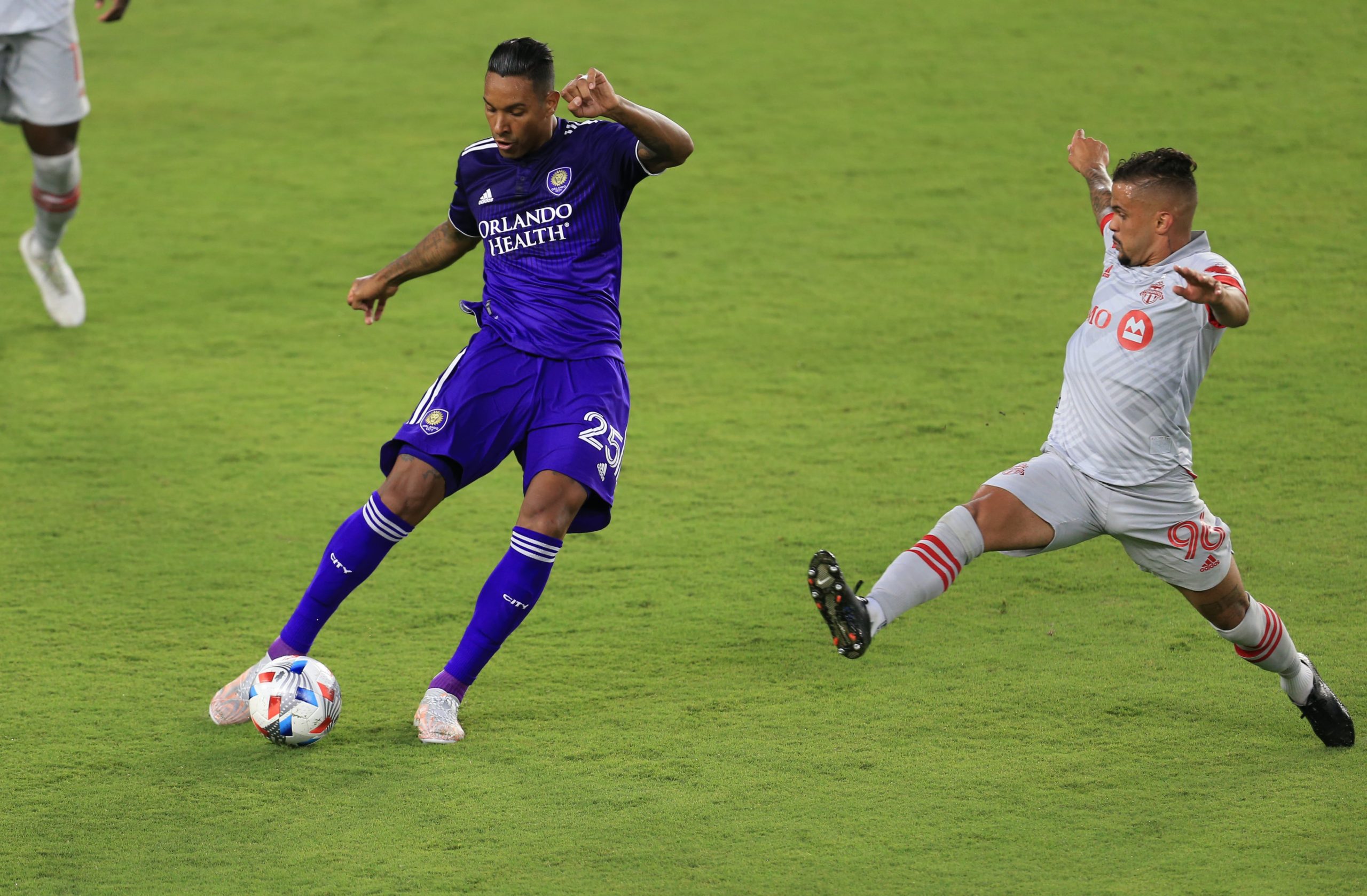 Orlando City defender Antonio Carlos (25) kicks the ball away from Toronto FC defender Auro (96) at Orlando City Stadium.
