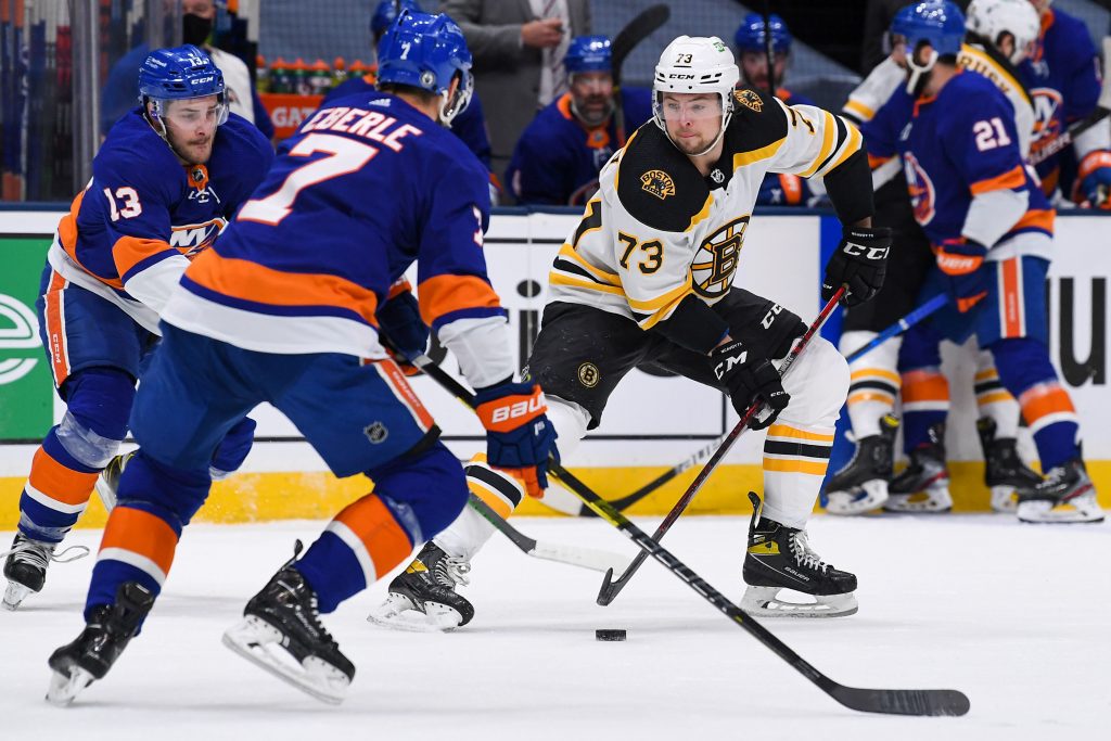 Jun 5, 2021; Uniondale, New York, USA; Boston Bruins defenseman Charlie McAvoy (73) controls the puck against New York Islanders center Mathew Barzal (13) and New York Islanders right wing Jordan Eberle (7) during the first period in game four of the second round of the 2021 Stanley Cup Playoffs at Nassau Veterans Memorial Coliseum.