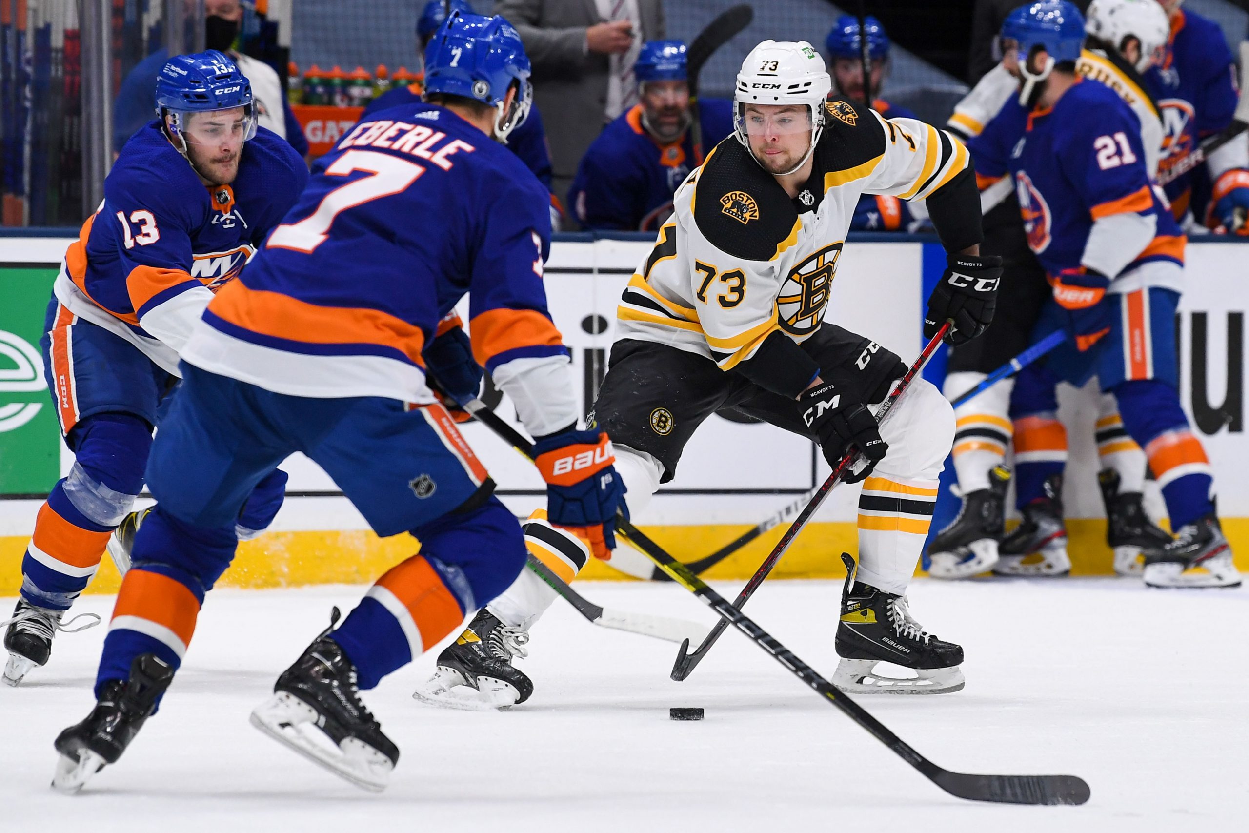 Jun 5, 2021; Uniondale, New York, USA; Boston Bruins defenseman Charlie McAvoy (73) controls the puck against New York Islanders center Mathew Barzal (13) and New York Islanders right wing Jordan Eberle (7) during the first period in game four of the second round of the 2021 Stanley Cup Playoffs at Nassau Veterans Memorial Coliseum.