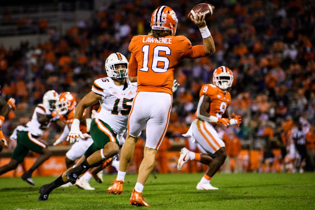 Clemson Tigers quarterback Trevor Lawrence (16) throws to running back Travis Etienne (9) against Miami Hurricanes defensive line Jaelan Phillips (15) during the first quarte at Memorial Stadium