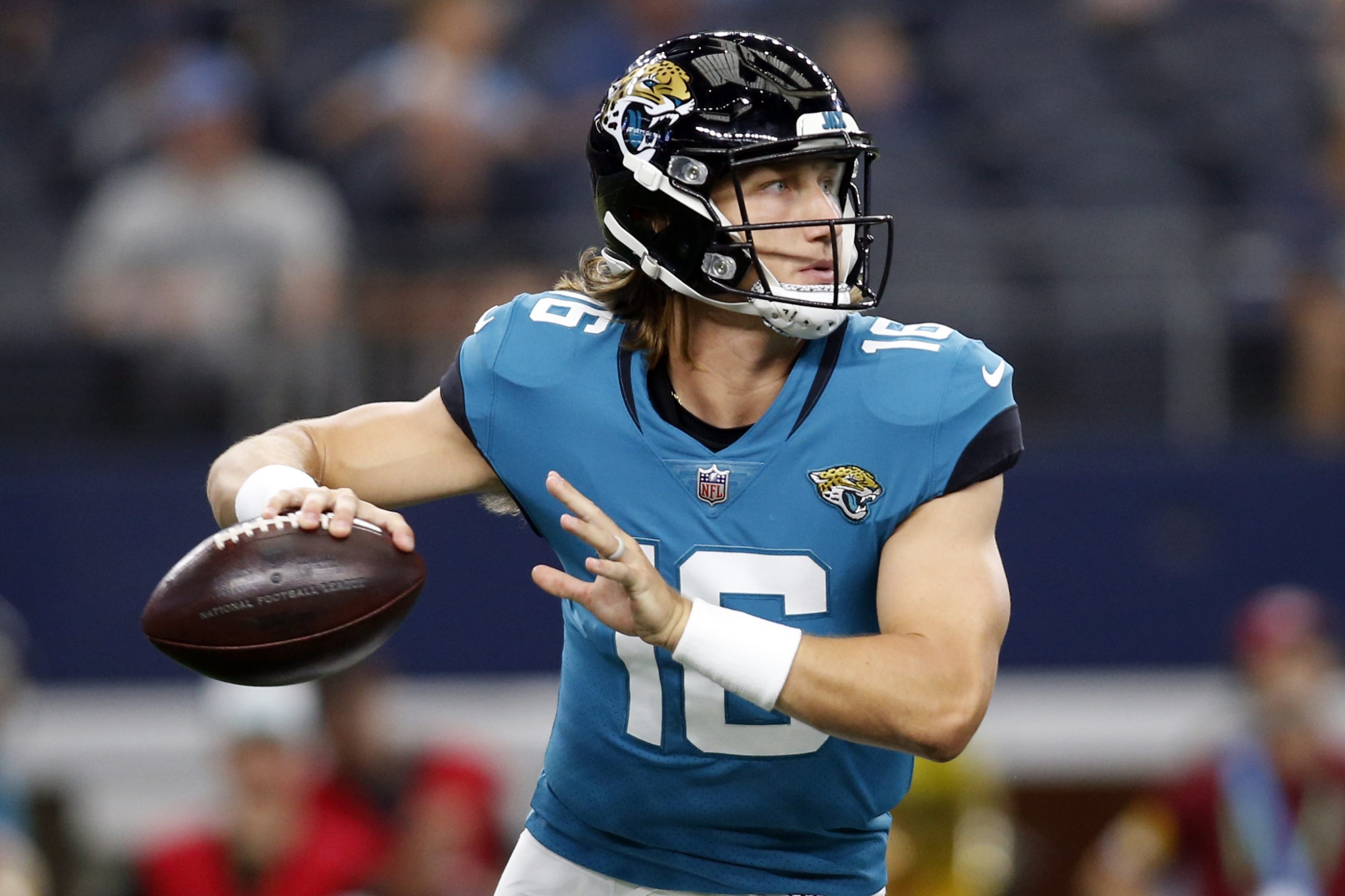 Jacksonville Jaguars quarterback Trevor Lawrence (16) rolls out to throw a pass in the first quarter of a preseason game against the Dallas Cowboys at AT&T Stadium.