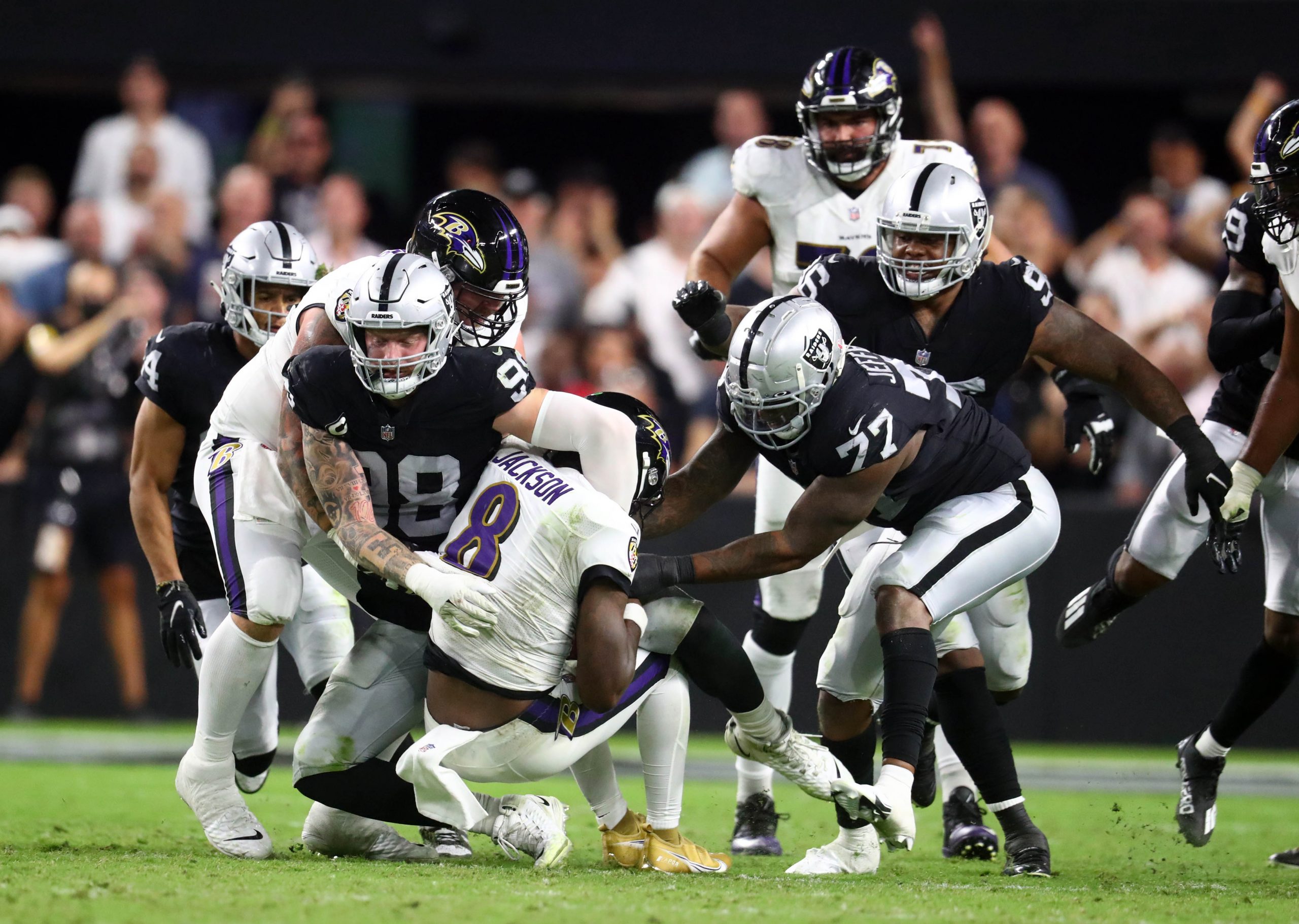 Baltimore Ravens quarterback Lamar Jackson (8) is brought down by Las Vegas Raiders defensive end Maxx Crosby (98) and defensive end Quinton Jefferson (77) during the second half at Allegiant Stadium