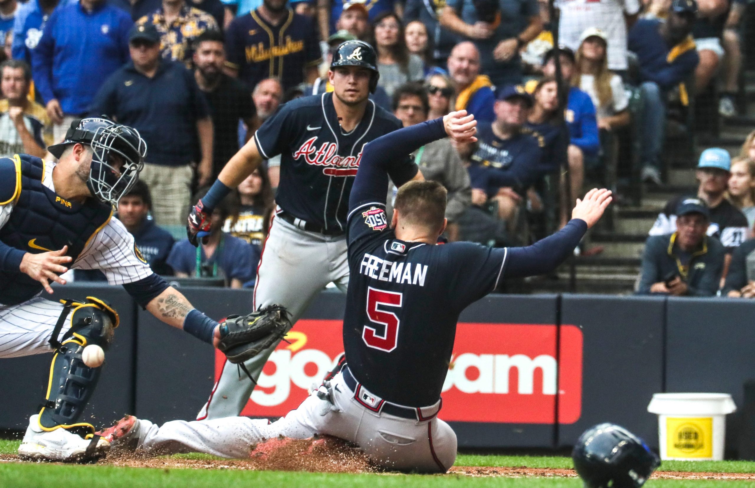 Braves first baseman Freddie Freeman slides safley into home as Brewers catcher Manny Pina is unable to handle the throw during the third inning of Game 2 parlay