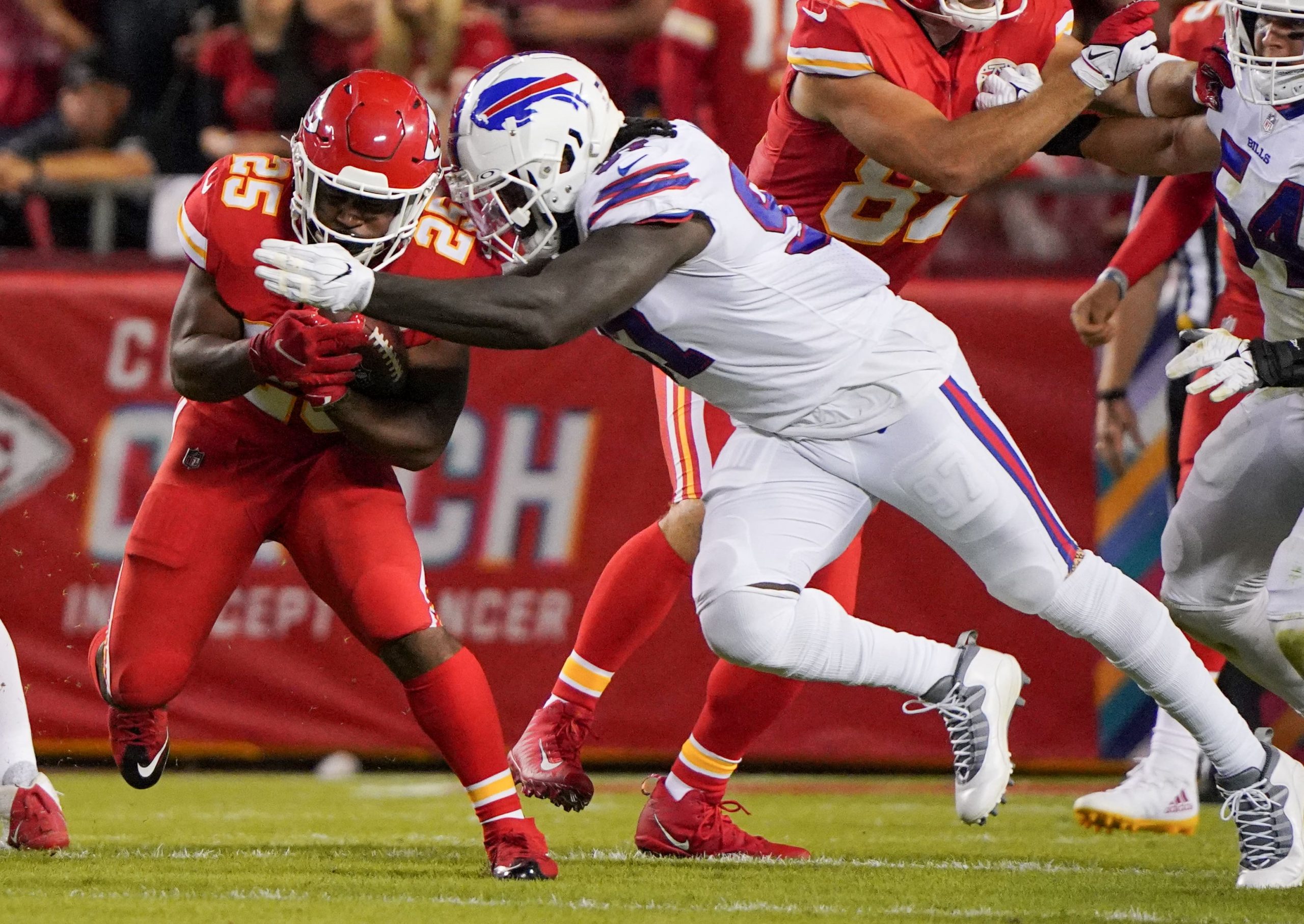 Kansas City Chiefs running back Clyde Edwards-Helaire (25) runs the ball as Buffalo Bills defensive end Mario Addison (97) makes the tackle during the first half at GEHA Field at Arrowhead Stadium
