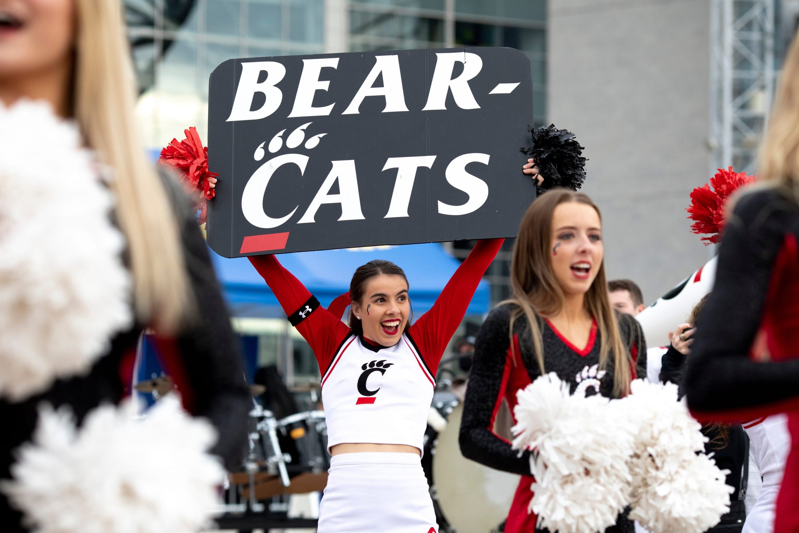 Cincinnati Bearcats cheerleader holds up a sign during the Cotton Bowl's Battle of the Bands between the University of Cincinnati band and the Alabama University's Million Dollar Band outside AT&T Stadium.