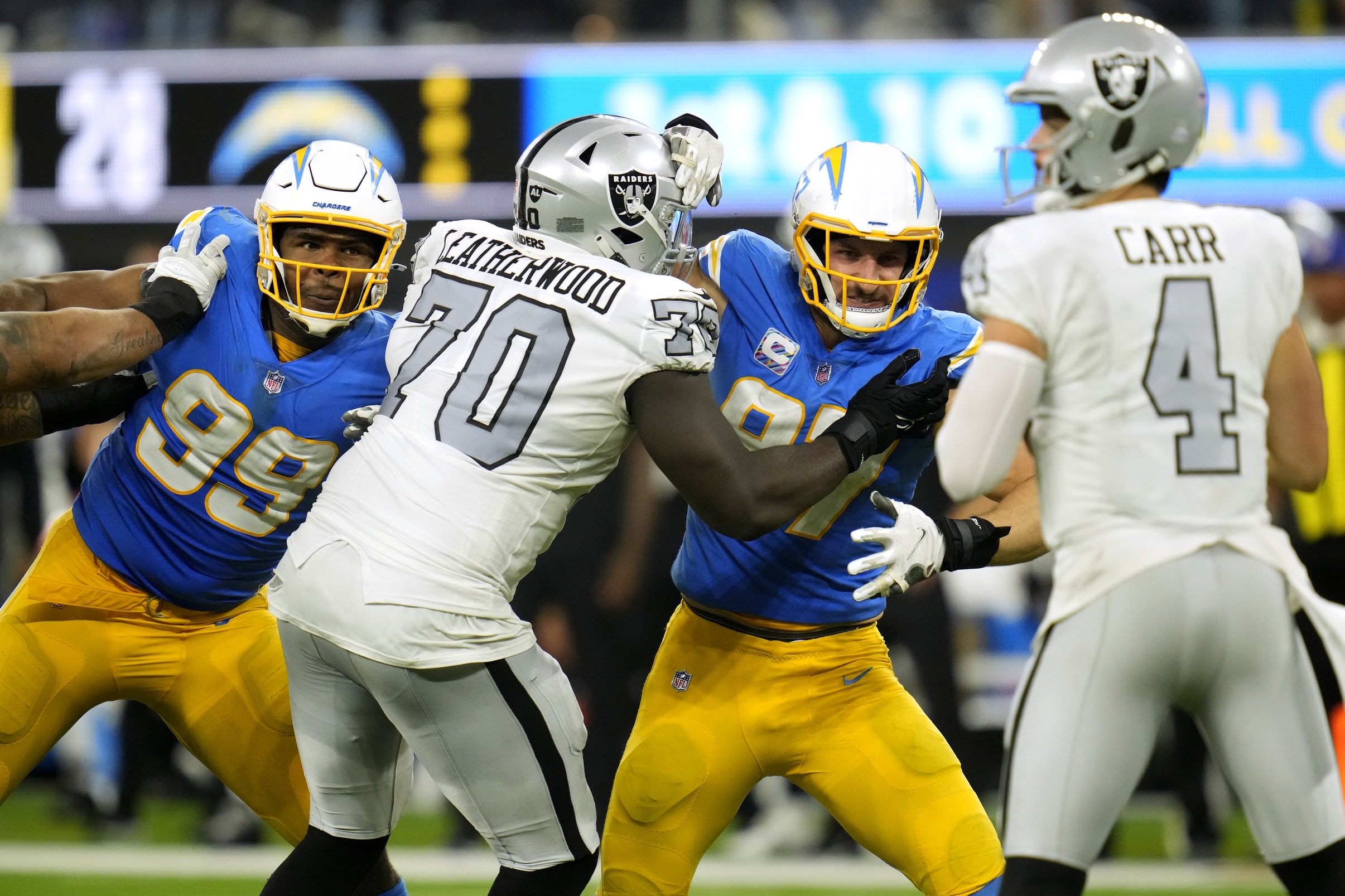 os Angeles Chargers defensive tackle Jerry Tillery (99) and defensive end Joey Bosa (97) battle against Las Vegas Raiders offensive tackle Alex Leatherwood (70) as Raiders quarterback Derek Carr (4) looks for a pass.