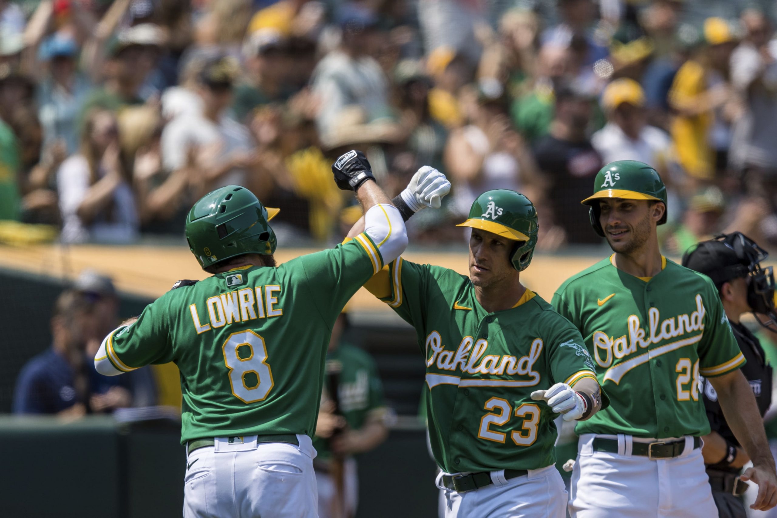 Oakland Athletics' Yan Gomes (23) celebrates with Jed Lowrie (8) and Matt Olson (28) after hitting a three-run home run against the Texas Rangers during the fourth inning of a baseball game in Oakland, Calif., Saturday, Aug. 7, 2021.