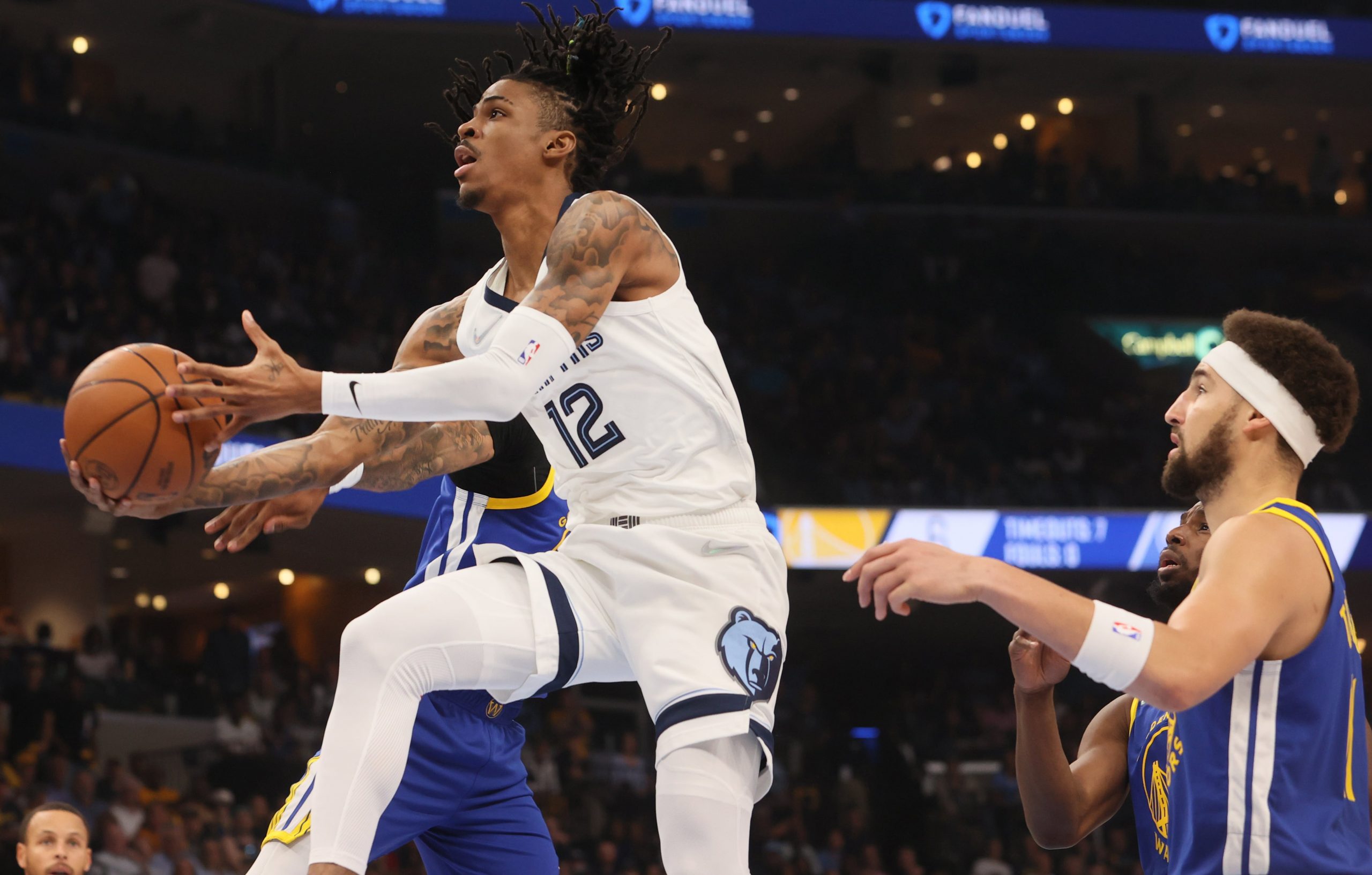 Memphis Grizzlies guard Ja Morant (12) lays the ball up past Golden State Warriors guard Klay Thompson (11) during game one of the second round for the 2022 NBA playoffs at FedExForum.