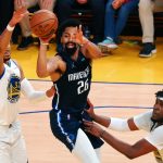 Dallas Mavericks guard Spencer Dinwiddie (26) passes the ball between Golden State Warriors forward Otto Porter Jr. (32) and center Kevon Looney (5) during the fourth quarter of game two of the 2022 Western Conference Finals.