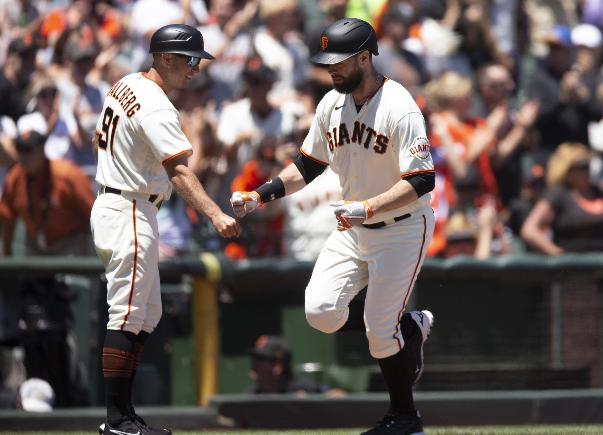 San Francisco Giants designated hitter Brandon Belt (right) celebrates with third base coach Mark Hallberg (91) after hitting a solo home run against the Kansas City Royals in the fourth inning at Oracle Park.
