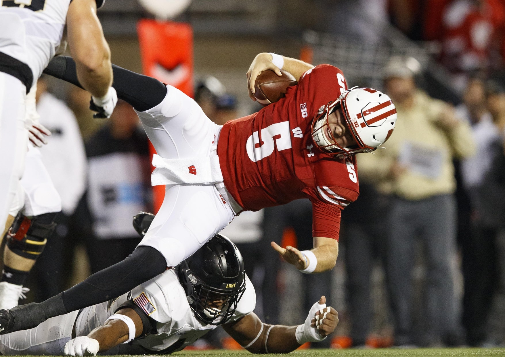 Oct 16, 2021; Madison, Wisconsin, USA; Wisconsin Badgers quarterback Graham Mertz (5) is tackled with the football during the first quarter against the Army Black Knights at Camp Randall Stadium.